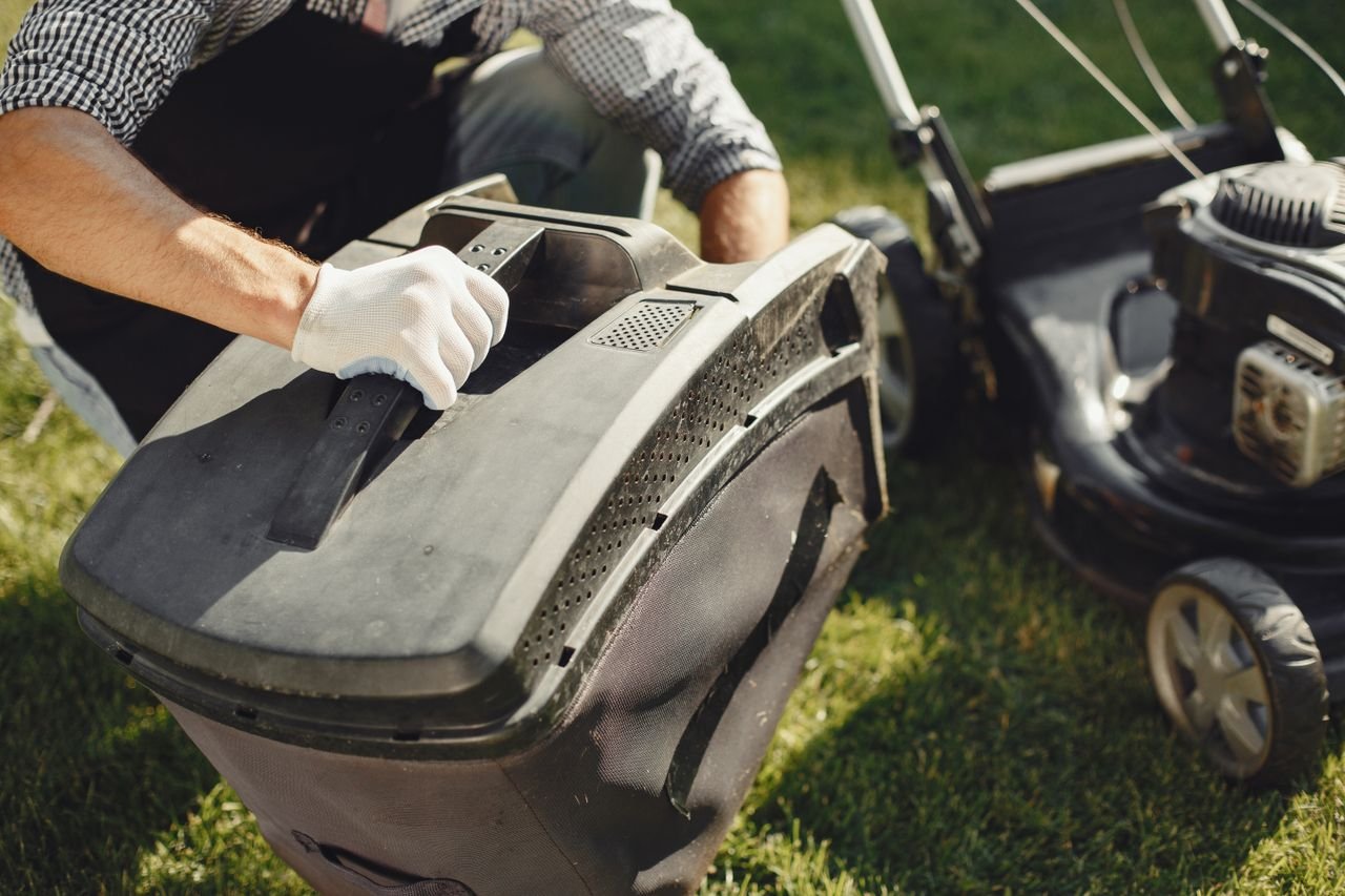 The Art of Drawing Readers In: Your attractive post title goes here An adult man replacing a lawn mower bag on a sunny day in the yard.